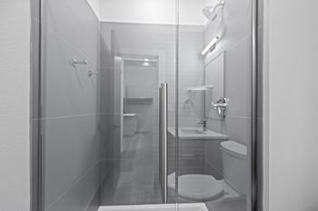 A bathroom with a toilet, sink, and shower at The Avenue Lofts Golden Apartments, Golden 80401
